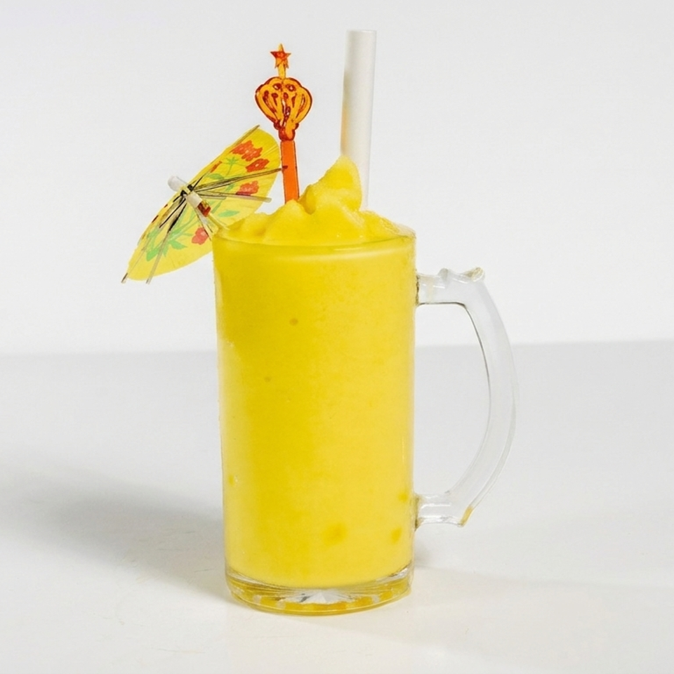 Bright yellow frozen drink in a handled glass mug, topped with a paper umbrella, straw, and decorative cocktail pick.