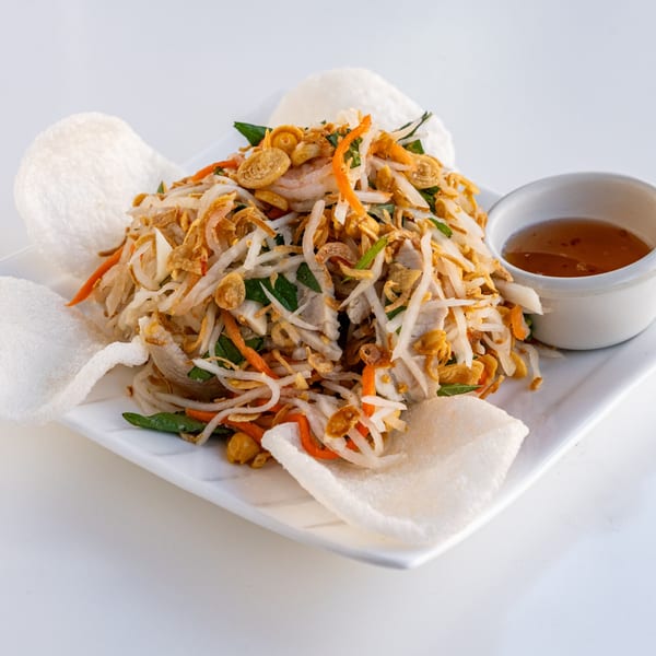 Shredded chicken and vegetable salad with crispy fried onions, served with rice crackers and dipping sauce.